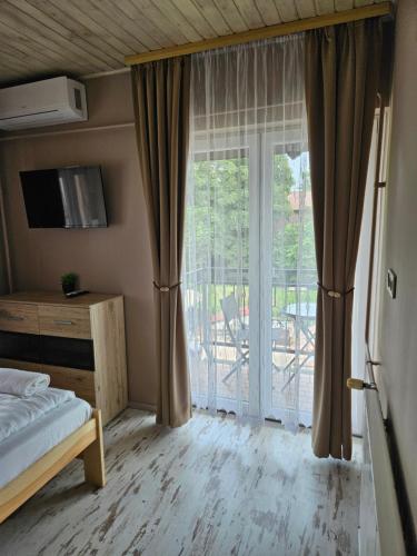 a bedroom with a bed and a sliding glass door at Villa Szófia in Siófok