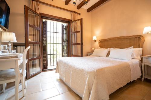 a bedroom with a bed and a desk and a window at Hotel Azalea Playa in Chiclana de la Frontera