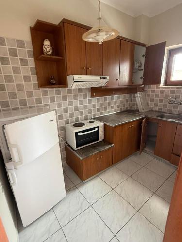 a kitchen with wooden cabinets and a white refrigerator at Aigeiros Apartments & restaurant in Skala Mistegnon