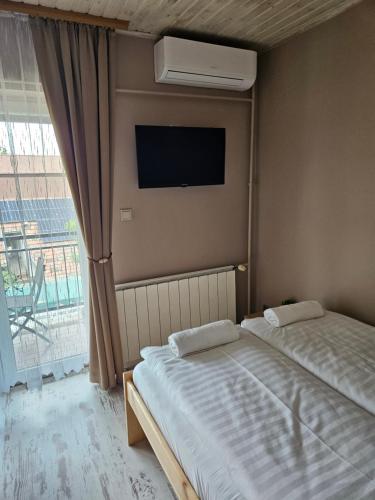 a bedroom with two beds and a tv and a window at Villa Szófia in Siófok