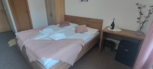 a bed with pink pillows and a wooden desk at Hotel Orlan in Bratislava