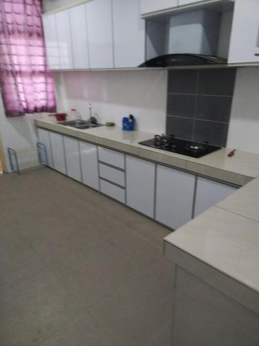a kitchen with white cabinets and a counter top at Homestay Atok Komando Bc Poly KB in Ketereh