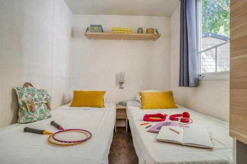 une chambre avec deux lits avec des livres et des lunettes dessus dans l'établissement Camping - Piscine - ccai0bg, à Argelès-sur-Mer