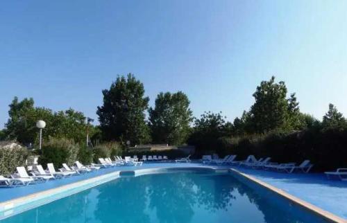 une grande piscine avec des chaises et des chaises blanches dans l'établissement Camping 3 étoiles - Piscine - ccb0dii, à Vias