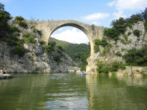 a bridge over a river with people kayaking under it at Respira Glamping Alta Garrotxa in Montagut