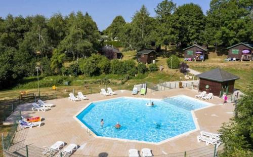 une grande piscine avec des personnes assises autour de celle-ci dans l'établissement Chalet 3 étoiles - Piscine - ccafecf, à Tauves