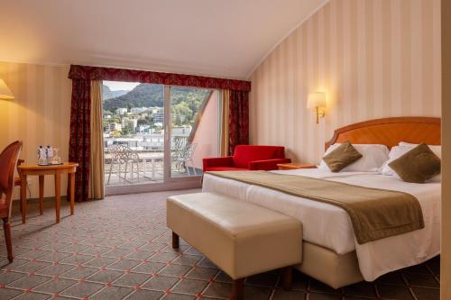 um quarto de hotel com uma cama grande e uma varanda em Hotel De La Paix em Lugano