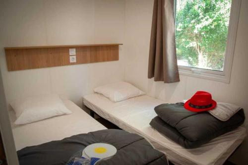 une chambre avec deux lits avec un chapeau rouge dessus dans l'établissement Camping 4 étoiles - Piscine - ccaffbg, à Villeneuve-lès-Béziers