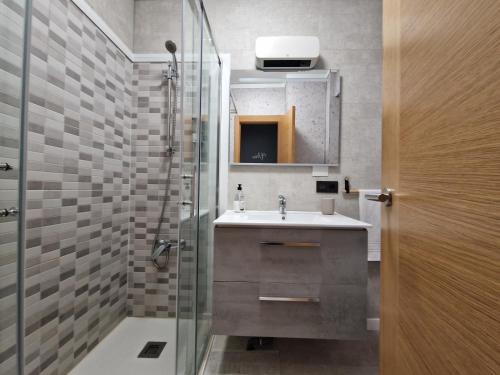 a bathroom with a sink and a glass shower at Apartamento Playa Bouzas - Vigo - Parking free in Vigo
