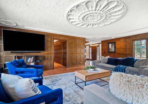 a living room with blue chairs and a tv at Unique Estate 5 Bedrooms Fire Pit Sleeps 10 in Akron