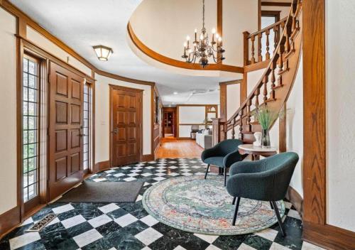 a hallway with two chairs and a table and stairs at Unique Estate 5 Bedrooms Fire Pit Sleeps 10 in Akron