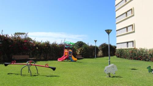 a park with childrens playground equipment in the grass at Cozy beach house in Skhirat