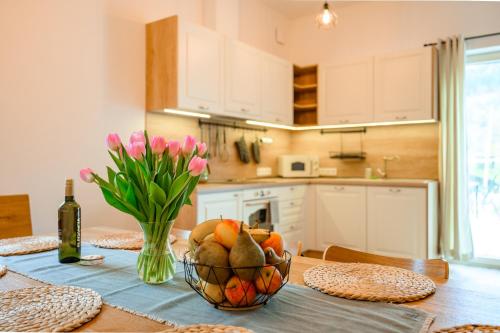 a kitchen with a table with a bowl of fruit and flowers at Dom pri jazere, Bešeňová in Bešeňová