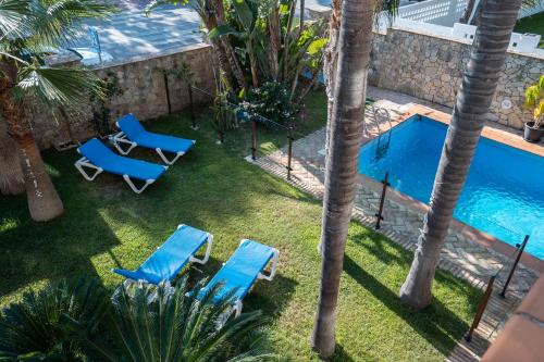 an overhead view of a swimming pool with two chairs and palm trees at Hotel Azalea Playa in Chiclana de la Frontera