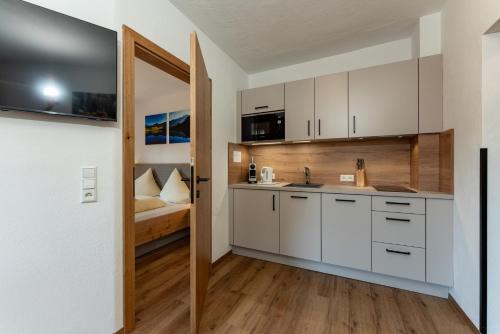 a kitchen with white cabinets and a bed at Pension Bergbauernhof Irxner in Schladming