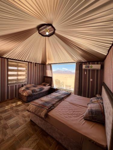 two beds in a room with a large window at Wadi Rum Mars Camp in Wadi Rum