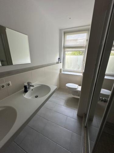 a white bathroom with a sink and a toilet at Bezaubernde Ferien- und Monteurswohnung Nahe Leipziger Zentrum in Leipzig