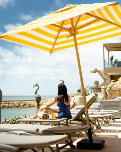 a woman sitting on a beach chair under an umbrella at Bavaro Beach Dakhla in Dakhla