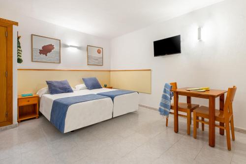 a bedroom with a bed and a table and a desk at Apartamentos Vibra Tropical Garden in Ibiza Town