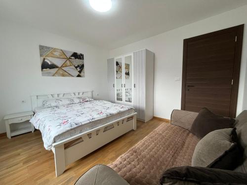 a white bedroom with a bed and a couch at Lux Apartment Rose Avenue 75m2 in Kragujevac