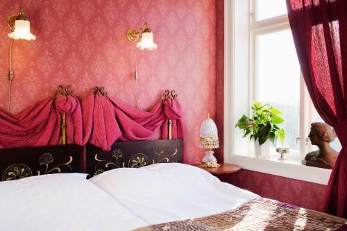 a bedroom with a bed with red walls and a window at Strandflickornas Havshotell Lysekil in Lysekil