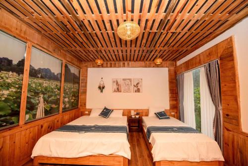 two beds in a room with wooden walls and windows at Hang Mua Luxury Homestay in Xuân Sơn