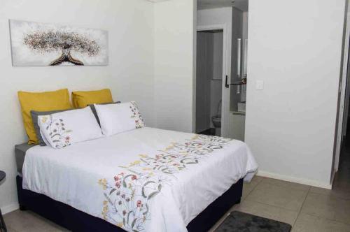 a bedroom with a bed with white sheets and yellow pillows at 2 Bedroom combo with pool at Ocean Dune, Sibaya in Umdloti