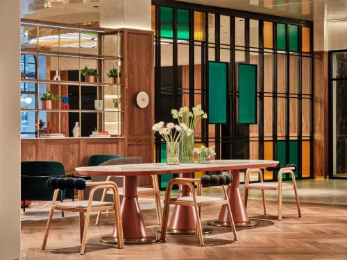 a table and chairs in a room with stained glass at Mövenpick Grand Hotel Wroclaw in Wrocław