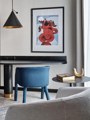 a living room with a blue chair and a picture at Mövenpick Grand Hotel Wroclaw in Wrocław