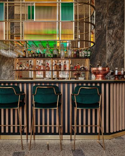 a bar with two green chairs in a room at Mövenpick Grand Hotel Wroclaw in Wrocław