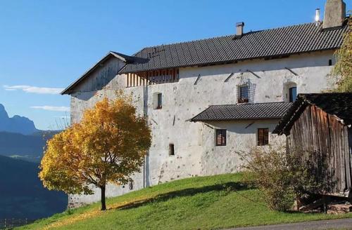 an old stone building on a hill with a tree at Schloss Gravetsch in Villandro