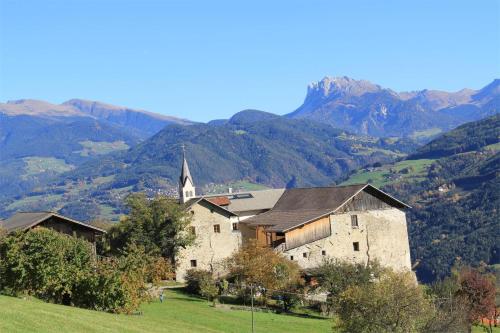 a church on a hill with mountains in the background at Schloss Gravetsch in Villandro