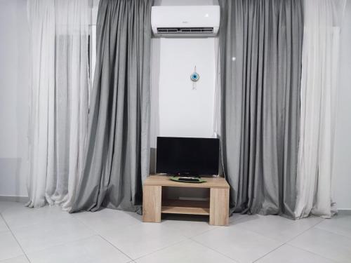 a television sitting on a table in front of curtains at Beautiful home for holidays in Mytilini