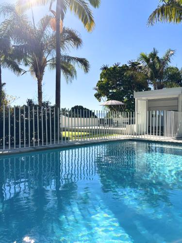 a swimming pool with a white fence and palm trees at The Paarl Grand in Paarl