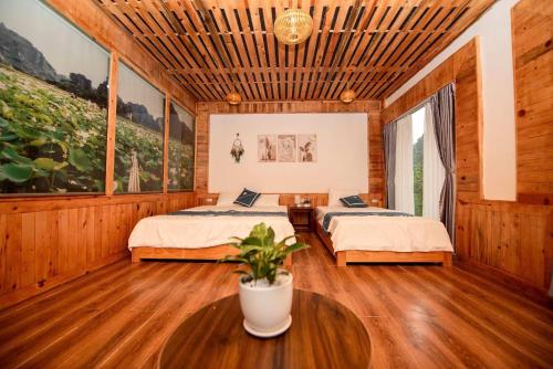 a bedroom with two beds and a table with a plant at Hang Mua Luxury Homestay in Xuân Sơn