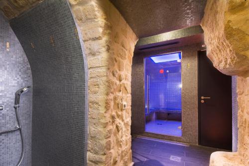a bathroom with a walk in shower next to a stone wall at Hôtel du Triangle d'Or - Proche Madeleine in Paris