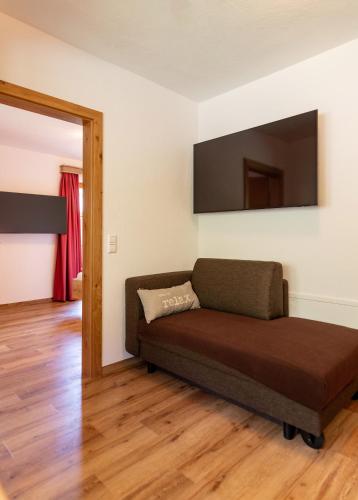 a living room with a couch and a flat screen tv at Pension Bergbauernhof Irxner in Schladming