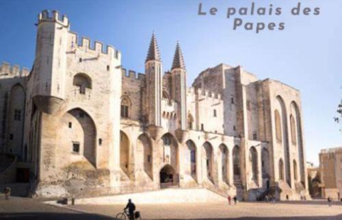 un bâtiment avec une personne faisant un vélo devant lui dans l'établissement Studio agréable aux portes des remparts, à Avignon