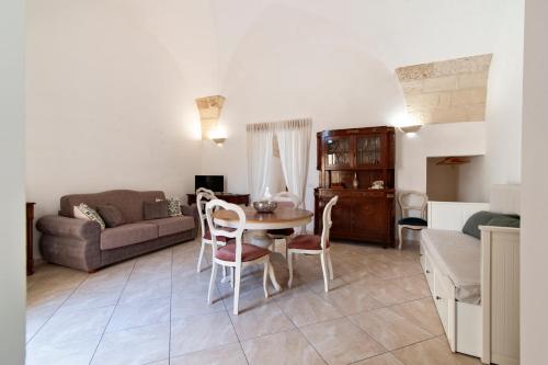 a living room with a table and chairs and a couch at Domus Aviae - No ZTL in Lecce
