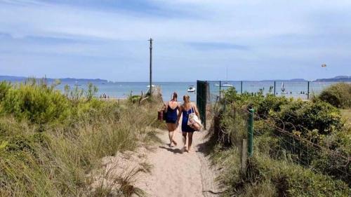 two women walking down a sandy path near the beach at Camping 4 étoiles - eebaeh in Hyères