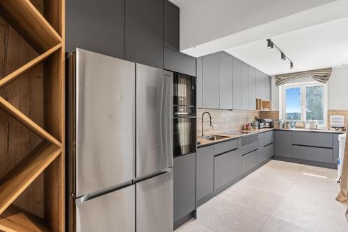 a kitchen with gray cabinets and a stainless steel refrigerator at Villa Salteria 3, pool, private territory, pinery in Rovinj