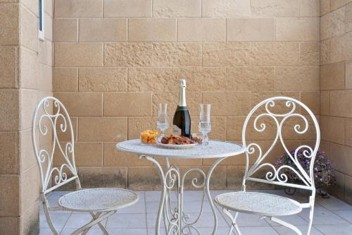 a table with two chairs and a bottle of wine at Domus Aviae - No ZTL in Lecce