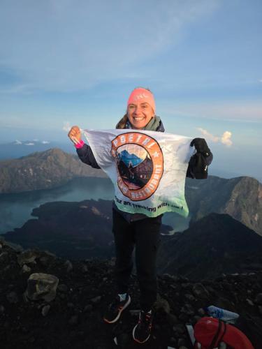 a woman standing on top of a mountain holding a flag at Poetri Bungalow & Restaurant in Senaru