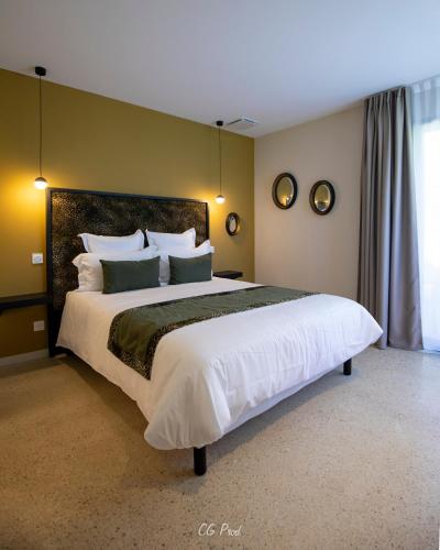 une chambre avec un grand lit avec des draps et des oreillers blancs dans l'établissement La Maison du Gindreau, à Saint-Médard