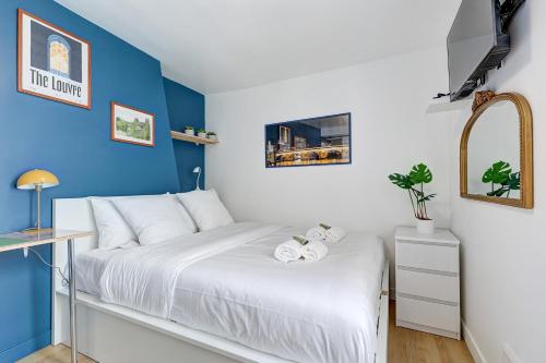 - une chambre dotée d'un lit blanc avec un mur bleu dans l'établissement Le Reve Parisien a Montorgueil, à Paris