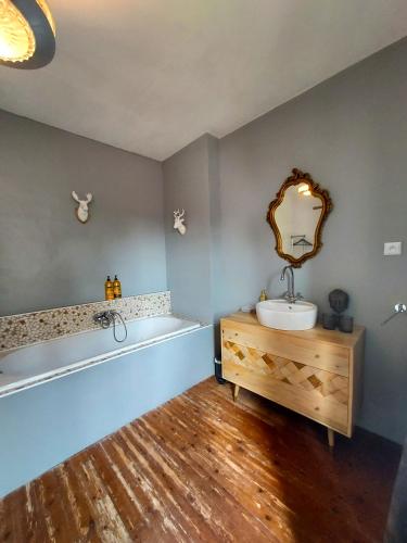 une salle de bain avec une baignoire, un lavabo et un miroir dans l'établissement Le Moulin en Route kamer rose en grijs, badkamer en suite, à Blèves