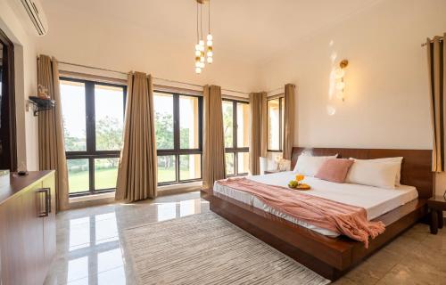 a bedroom with a large bed and large windows at MiAmor by The StayCationer in Manesar