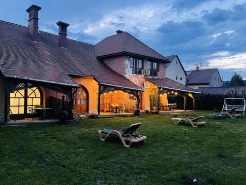 a house with two lounge chairs in the yard at GreenPark Garden Villa Family Apartments Near Tokaj in Szerencs