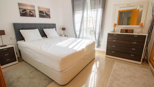 Un dormitorio con una gran cama blanca y una cómoda. en Lira 1013, en San Juan de los Terreros