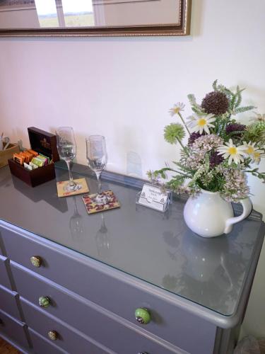 a dresser with a vase of flowers and wine glasses at Tarskavaig B&B in Radernie